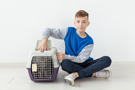 笑笑的男孩拿着一个笼子和一只苏格兰折叠猫坐在他旁边 坐在新公寓的地板上 保护宠物的概念毛皮折叠虎斑眼睛猫咪尾巴工作室动物晶须婴儿图片