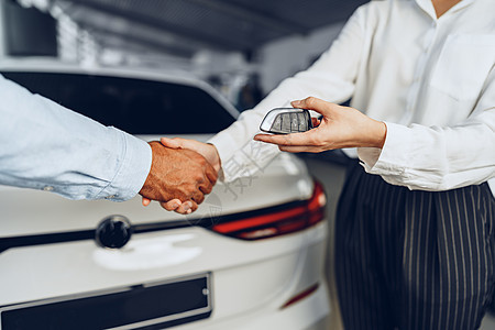 汽车销售商和买方在汽车经销商对一辆新车问题上握握手购物者交易人士推销员销售零售商业行政购物合同图片