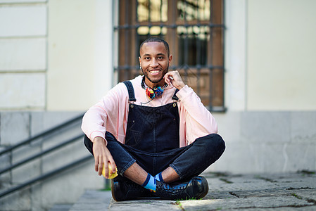 黑人年轻人坐在城市的阶梯上吃苹果水果食物牛仔布衣服毛衣快乐健康黑色成人男性图片