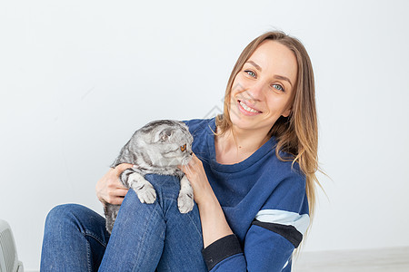 迷人的正派年轻女人手里握着 她美丽的灰色折叠苏格兰猫 坐在地上 在新公寓里 宠物概念伴侣小猫动物晶须尾巴眼睛猫咪哺乳动物折叠虎斑图片