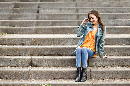 在城市阶梯上穿着便衣的漂亮头发的女人女性黑发女孩街道快乐楼梯成人牛仔布时尚衣服图片