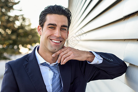年轻商务人士身穿蓝西装 在城市背景中领带微笑管理人员男人公司成功衬衫企业家工作男性经理图片