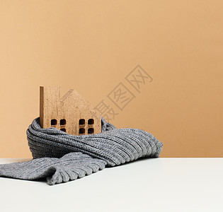 裹着灰色针织围巾的木制微型房子 建筑保温概念 维修贷款图片