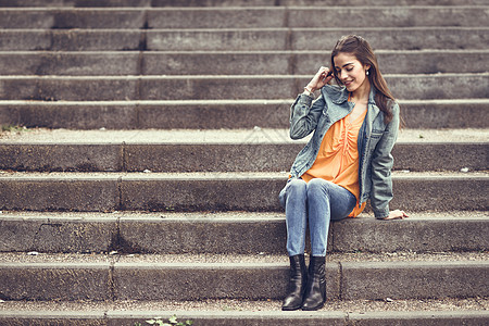 在城市阶梯上穿着便衣的漂亮头发的女人女孩快乐女性微笑成人牛仔布街道发型时尚黑发图片