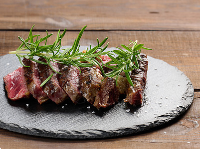 在黑板上切成碎片的炸牛肉肉 鲜有熟食度 美味牛排肋眼烧烤香料红色桌子牛扒食物草本植物木板牛肉图片