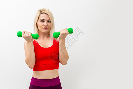 运动妇女用灰色背景的哑铃抽动肌肉肌肉女性身体活动成人头发微笑重量训练运动员女孩图片