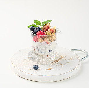 透明玻璃 加花粉和酸奶 在成熟的草莓 蓝莓和白桌上的无花果上浇注覆盆子水果玻璃奶制品粮食蓝色营养早餐桌子食物图片