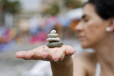 具有海背景的妇女手中堆积的石块天空鹅卵石岩石碎石海洋女士精神手指生长治疗图片