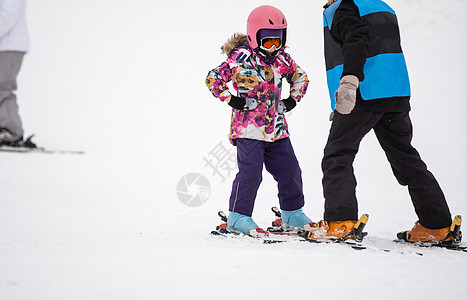 专业的滑雪教练正在教一个孩子在有雪的山坡度假村滑雪一天 家庭和儿童积极度假图片