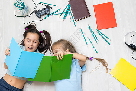 两个小女孩姐妹 读一本书躺在地板上写着说谎童年地毯乐趣教育闲暇女孩地面孩子评书图片