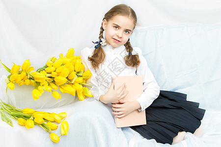 一位有黄色郁金香的勤奋女学生坐在T女性展示微笑粉色礼物花束裙子白色花朵母亲图片