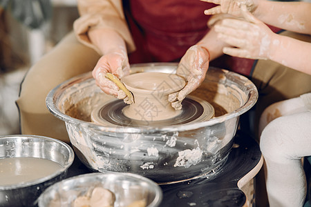 母亲和女儿在陶器学校做花瓶手工黏土老师制品桌子班级职业车轮艺术家黑发图片