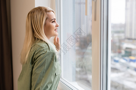 年轻女人站着看窗外的女青年窗帘窗户头发沉思幸福咖啡日光女孩期望警报图片