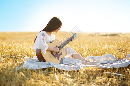 夏天是一个伟大的梦幻时光 美丽的女孩在小麦田里弹吉他图片