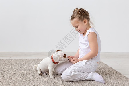 动物 儿童和宠物概念     小女孩与可爱的小狗一起坐在地板上玩耍朋友孩子食物亲热盘子婴儿友谊童年房间犬类图片