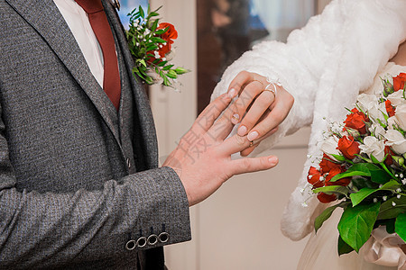 新娘的手把结婚戒指放在新郎的拇指上男人成人妻子订婚金子套装面纱女性婚姻家庭图片