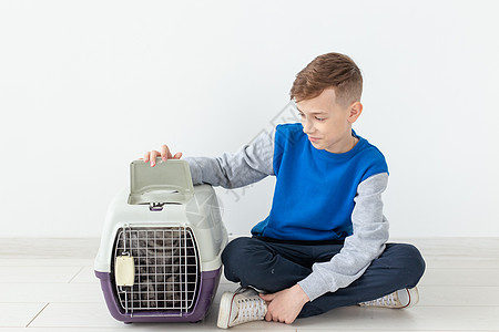 笑笑的男孩拿着一个笼子和一只苏格兰折叠猫坐在他旁边 坐在新公寓的地板上 保护宠物的概念折叠哺乳动物工作室眼睛猫咪乐趣短发虎斑婴儿图片