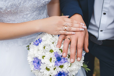 新娘和新郎在婚礼花束上的温柔和黄鼠狼的手图片