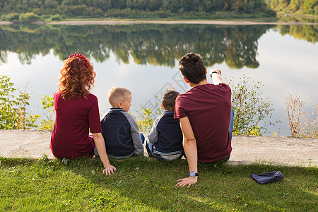 童年和自然概念     家庭 小儿子坐在绿草上乐趣父亲衬衫公园儿子们池塘女士儿子爸爸天空图片