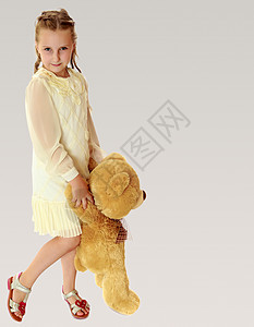 带着泰迪熊的漂亮小女孩微笑乐趣玩具婴儿灰色女孩童年孩子图片