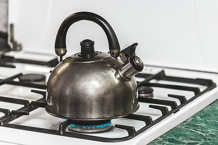 含口哨的金属黑水壶将水加热到厨房一个煤气炉灶上煮沸厨具烹饪用具器具美食合并反射蓝色火炉火焰图片