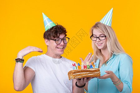 年轻开朗的学生迷人的女孩和拿着蛋糕的问候纸帽的好人 祝贺生日和周年纪念日的概念问候语创造力艺术喜悦蓝色潮人礼物惊喜节日派对图片