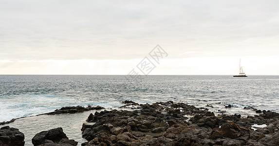 清晨平静的海洋 海边有石块旅行戏剧性海景石头海岸支撑蓝色天空巨石海浪图片