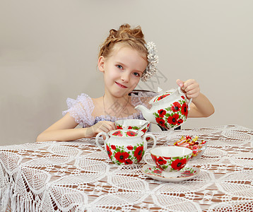 可爱的小女孩在旧桌边喝茶孩子们女性杯子微笑食物童年裙子青年孩子幸福图片