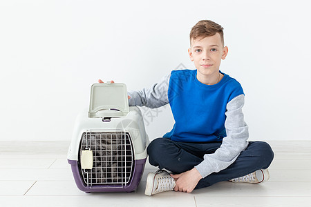笑笑的男孩拿着一个笼子和一只苏格兰折叠猫坐在他旁边 坐在新公寓的地板上 保护宠物的概念乐趣折叠工作室毛皮晶须婴儿小猫虎斑动物哺乳图片
