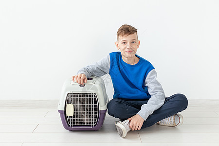 笑笑的男孩拿着一个笼子和一只苏格兰折叠猫坐在他旁边 坐在新公寓的地板上 保护宠物的概念动物毛皮折叠眼睛乐趣尾巴短发婴儿晶须哺乳动图片