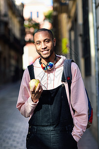 黑人年轻人在街上吃苹果 走在街上食物胡须健康城市成人水果毛衣黑色男性休闲服图片