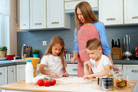年轻母亲和她可爱的孩子一起做比萨饼家庭父母食物面粉蛋糕童年女儿围裙妈妈滚动图片