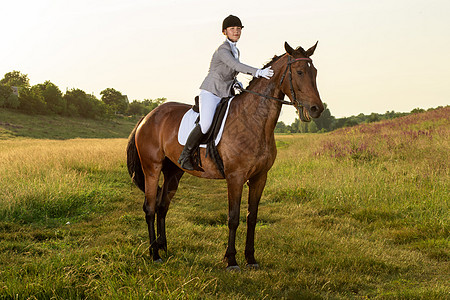 马术运动 年轻女子骑马参加着装高级试练专注测试骑马者晴天运动课程皮革女性场地舞步图片