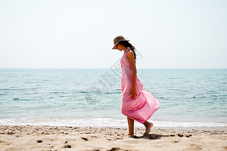 在热带沙滩上穿长着粉红裙子的漂亮女人女性头发季节双臂喜悦女孩旅行旅游闲暇棕褐色图片