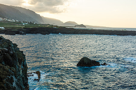 一具水体 其背景是山峰太阳海岸线海浪海洋地平线蓝色海岸石头海景场景图片