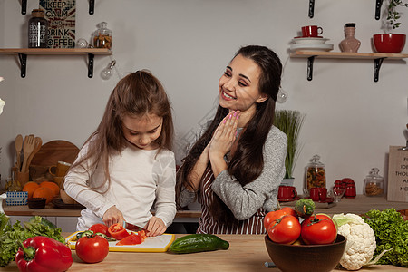 母亲和女儿正在做蔬菜沙拉 在厨房里玩得开心呢女孩父母青菜灯泡烹饪货架胡椒女性食物黑发图片