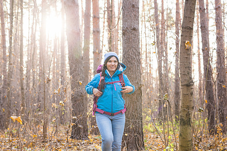 冒险 旅行 旅游 远足和人的概念  在森林深处行走的迷人微笑旅游女性季节树叶行动游客旅行者帽子背包小路运动夹克图片