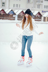 穿白色毛衣的漂亮可爱女孩 在冬天的城市滑冰化妆品竞技场乐趣微笑享受牛仔裤季节蓝色帽子图片