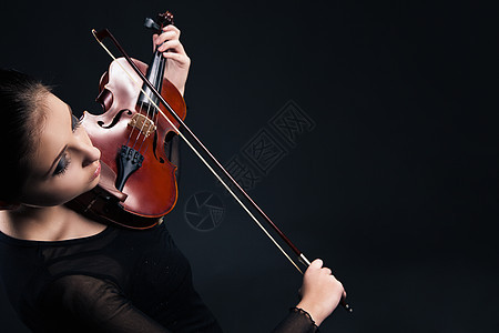 美丽的年轻女士 在黑色上拉小提琴学生音乐会玩家乐器乐队中提琴娱乐音乐音乐家成人图片