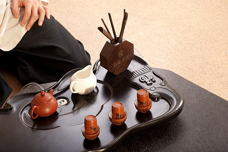 年轻男子举行中华茶礼仪式古董专注黑发传统地面茶壶服务木头男人图片
