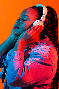 非洲女人年轻非洲女性用耳机聆听音乐的尼昂肖像微笑派对女士说唱艺术歌手工作室快乐爆炸收音机背景