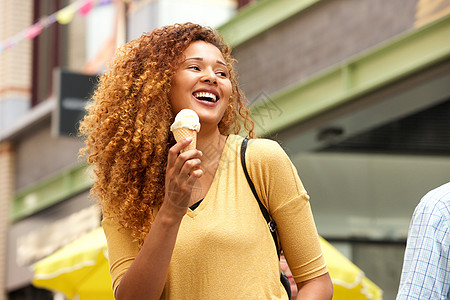 快乐的年轻女子在城市里笑着吃冰淇淋图片