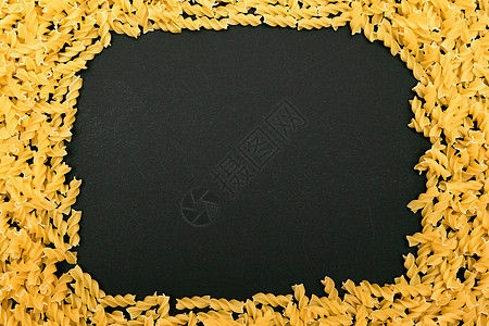 由黑桌上未烹调的粉碎成的框架小麦螺旋粉面食食物美食螺丝生食小样图片