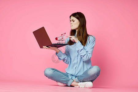 妇女坐在地板上 有笔记本电脑 购物娱乐和粉红色背景电子商务女士地面房间商业女性白色粉色网络信用图片