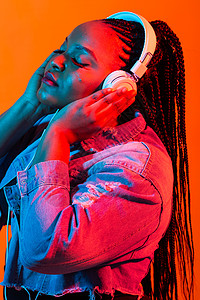 非洲女人年轻非洲女性用耳机聆听音乐的尼昂肖像爆炸女士派对微笑工作室收音机歌手玩家说唱快乐背景