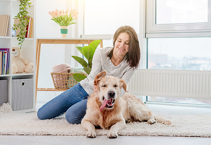 快乐的年轻女孩宠爱金色寻金犬猎犬房间宠物友谊犬类哺乳动物地面女士成人地毯图片