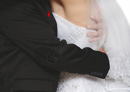 身穿黑色时尚西装的新郎穿着白色特写礼服紧紧拥抱新娘 婚礼的柔情与深情图片