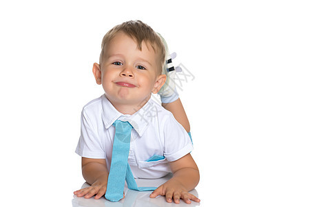 有个小男孩躺在工作室的地板上白色童年姿势男性幸福蓝色乐趣地面快乐喜悦图片