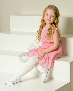 美丽的小女孩坐在白色的楼梯上 笑声乐趣工作室享受女性孩子粉色阁楼童年教育裙子图片