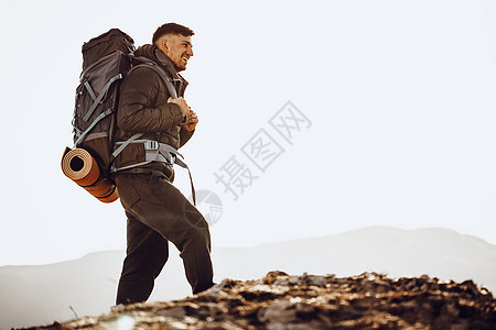 在山顶站立的徒步旅行设备中的男性背包男岩石耐力顶峰旅游地平线自由远足运动游客男人图片